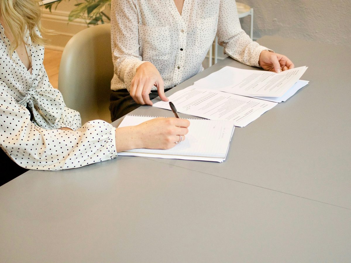 Cliente assinando um documento ao lado da contadora